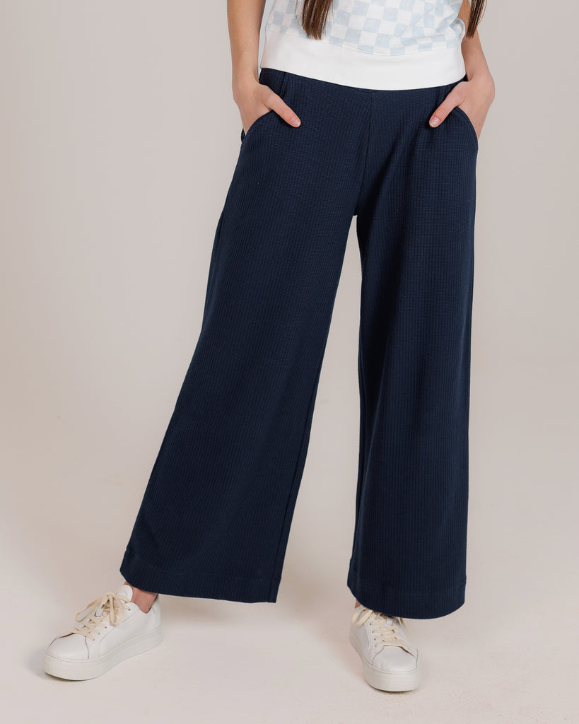 Model wearing a dark blue, flared, cropped, sweatpant.