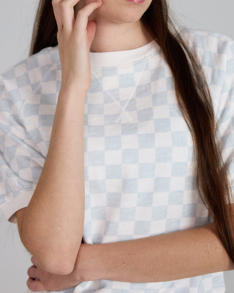 Model wearing a white and blue check short sleeve crew neck t-shirt.