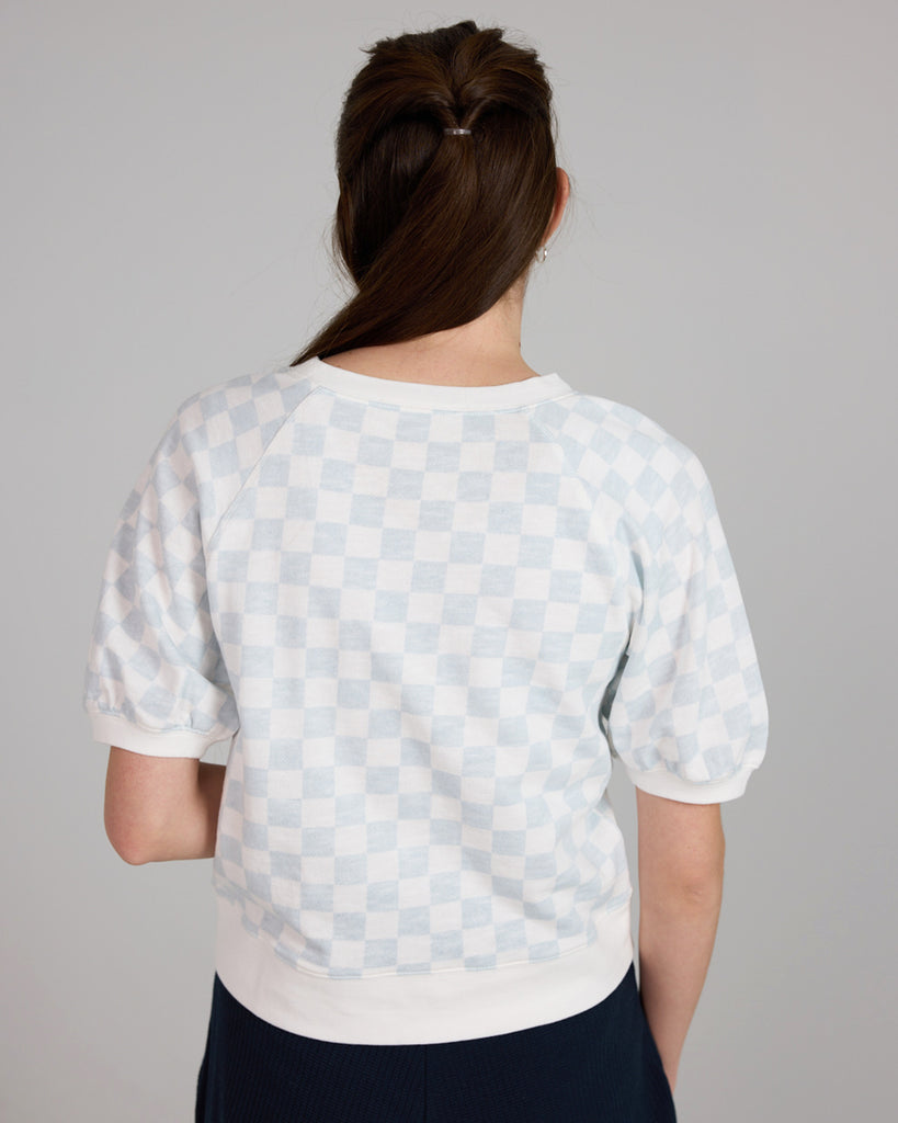 Model wearing a white and blue check short sleeve crew neck t-shirt.