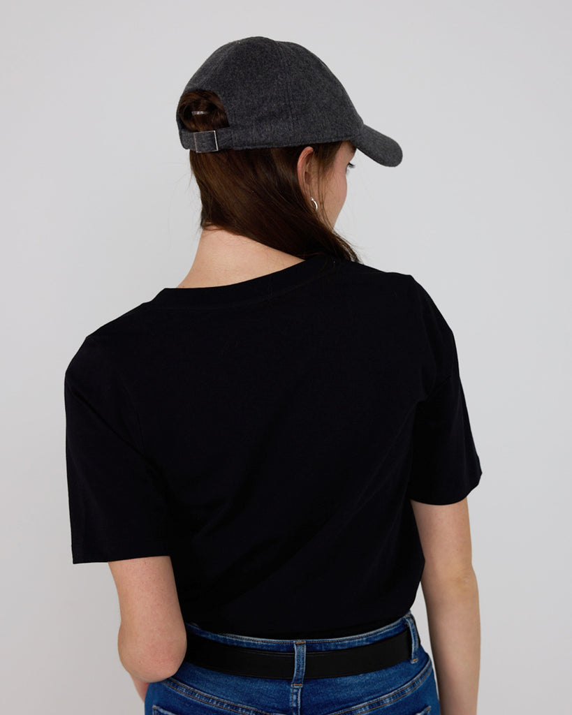 Back view of model wearing a black relaxed fit, short sleeve, v-neck basic tee.