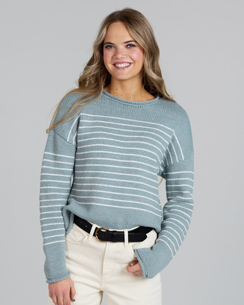 Model wearing a light blue with white stripes, logn sleeve, rolled round neck, dropped sleeve pullover sweater.