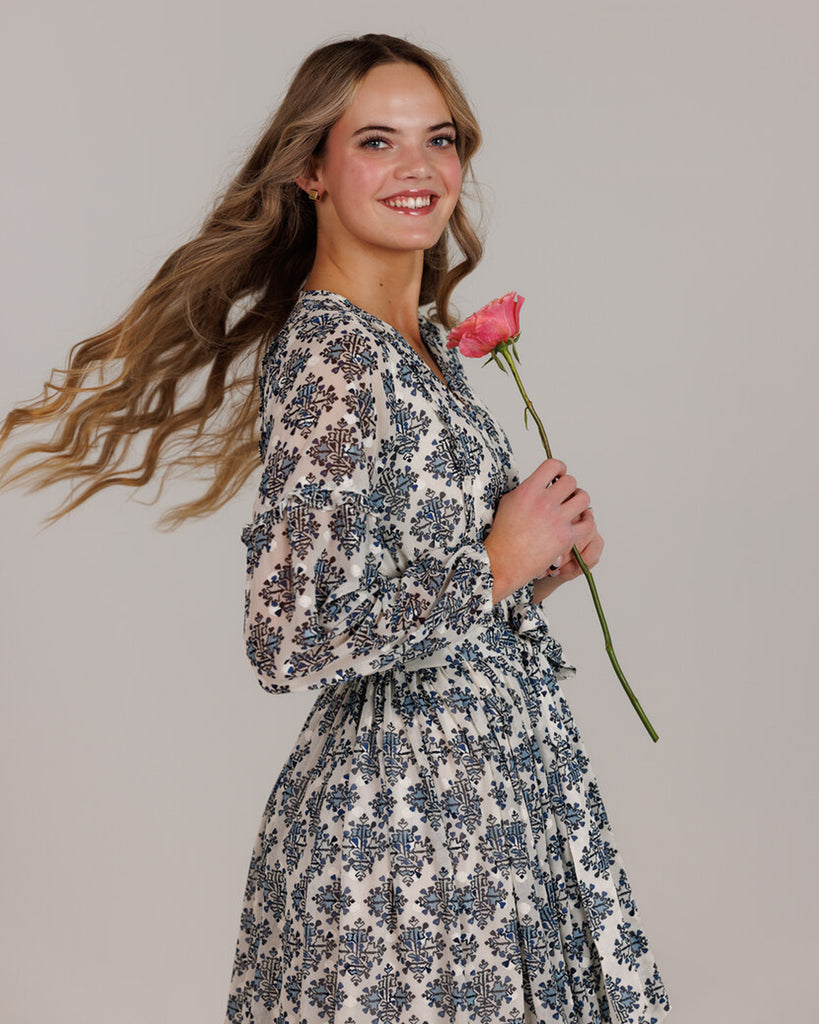 Model wearing a white and blue maxi length long sleeve dress.