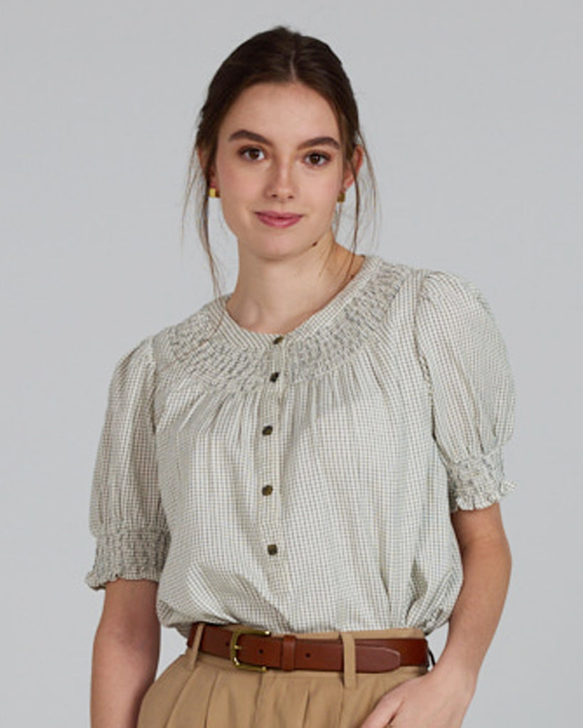 Model wearing a beige short sleeve blouse with button details and a small plaid pattern.