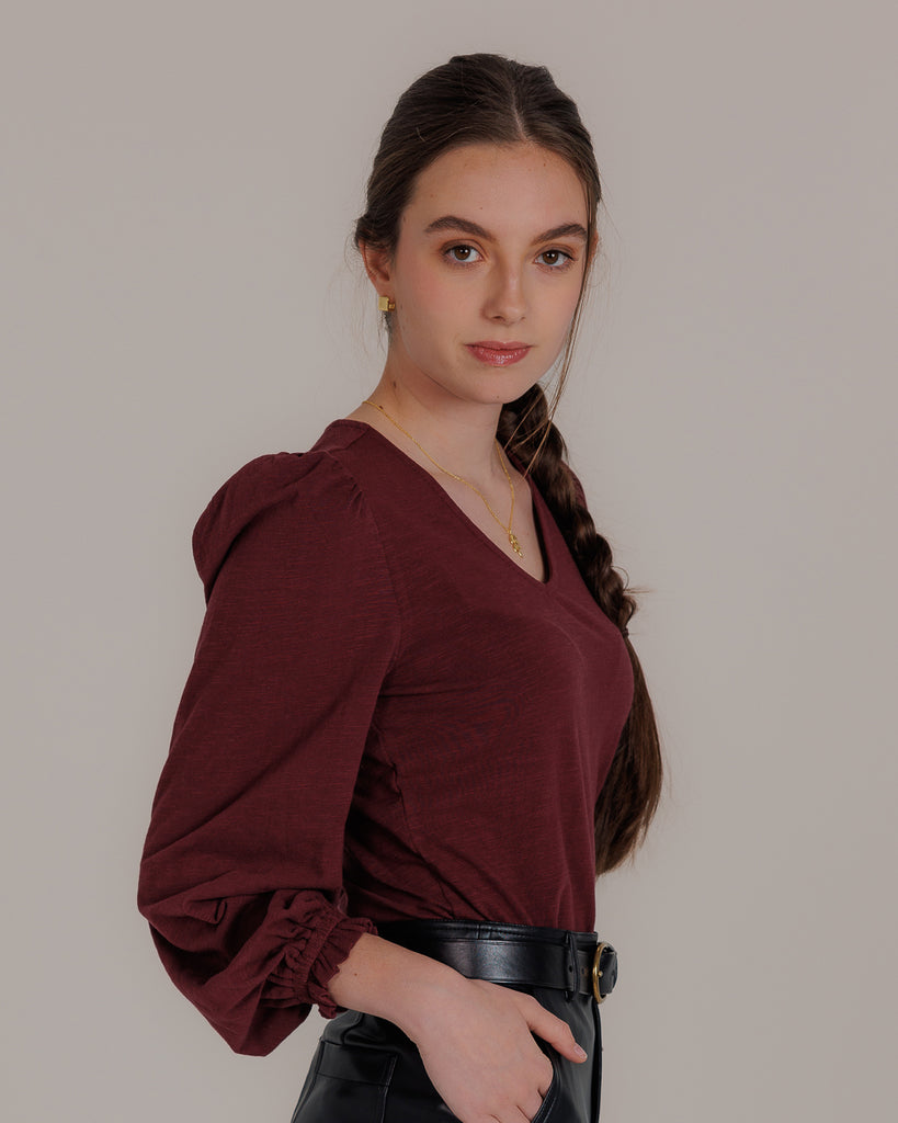 Model wearing a burgundy long balloon sleeve, v-neck knit top.