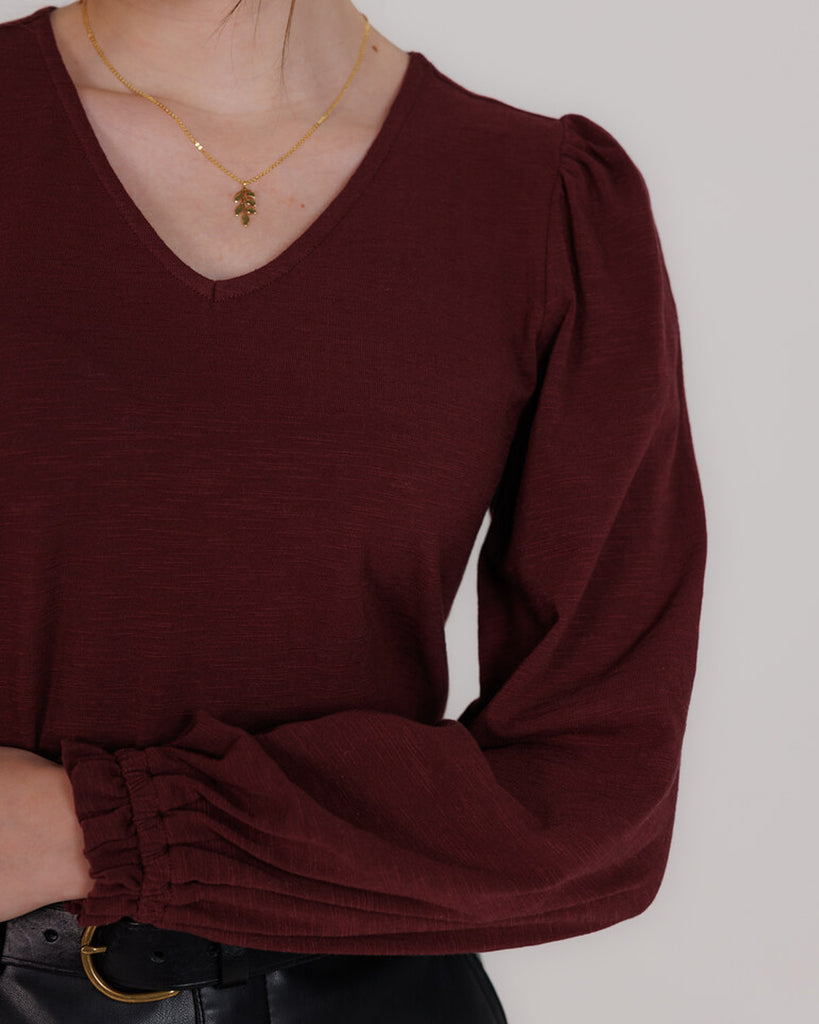 Model wearing a burgundy long balloon sleeve, v-neck knit top.