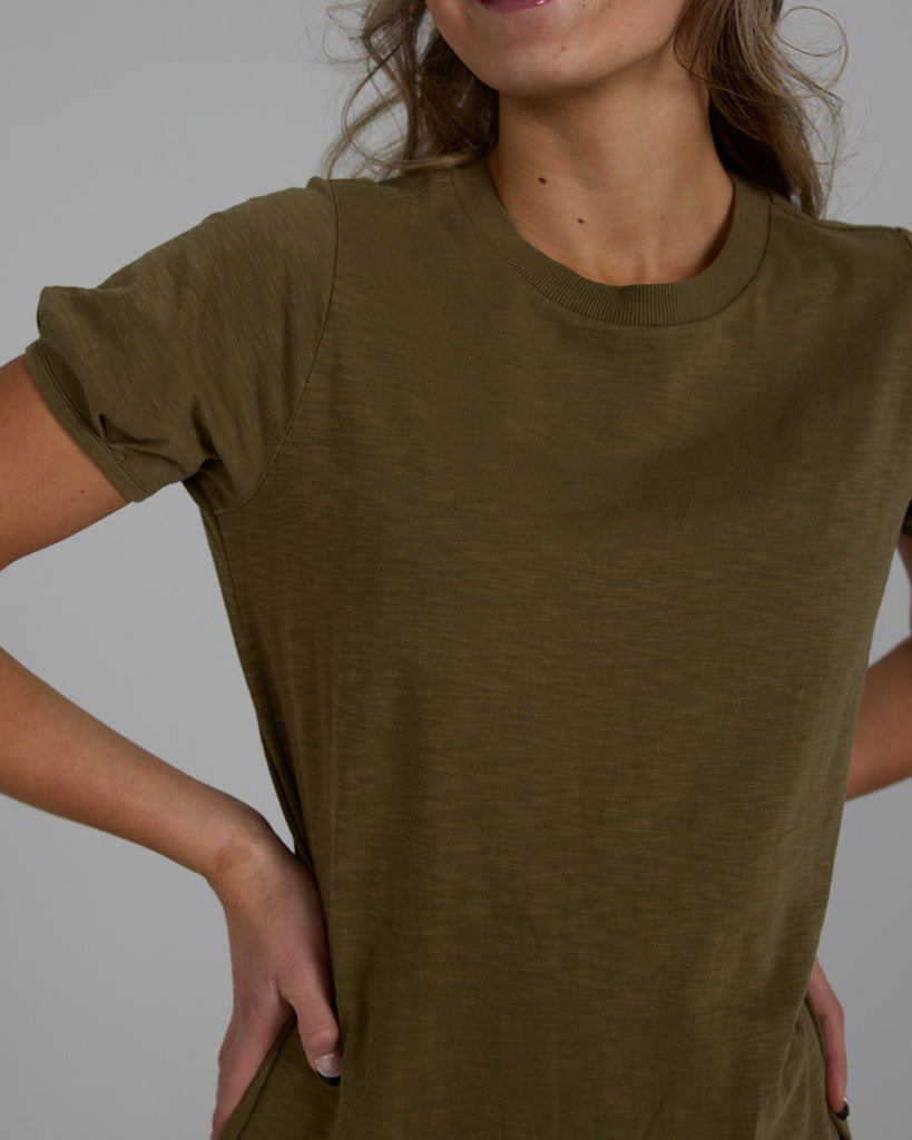 Model wearing an olive green short sleeve, crew neck, midi-length knit dress.