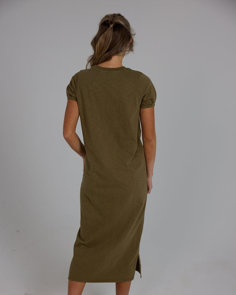 Model wearing an olive green short sleeve, crew neck, midi-length knit dress.